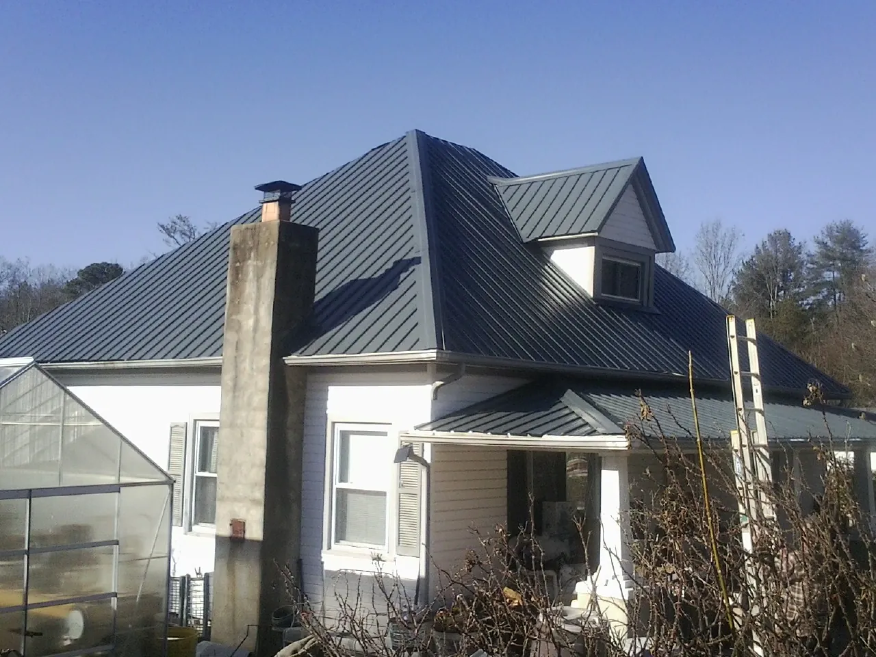 Dark blue standing seam metal roof on a white farmhouse with dormer — Slate & Tile Roof Repair by Roofing Brothers in Ringgold