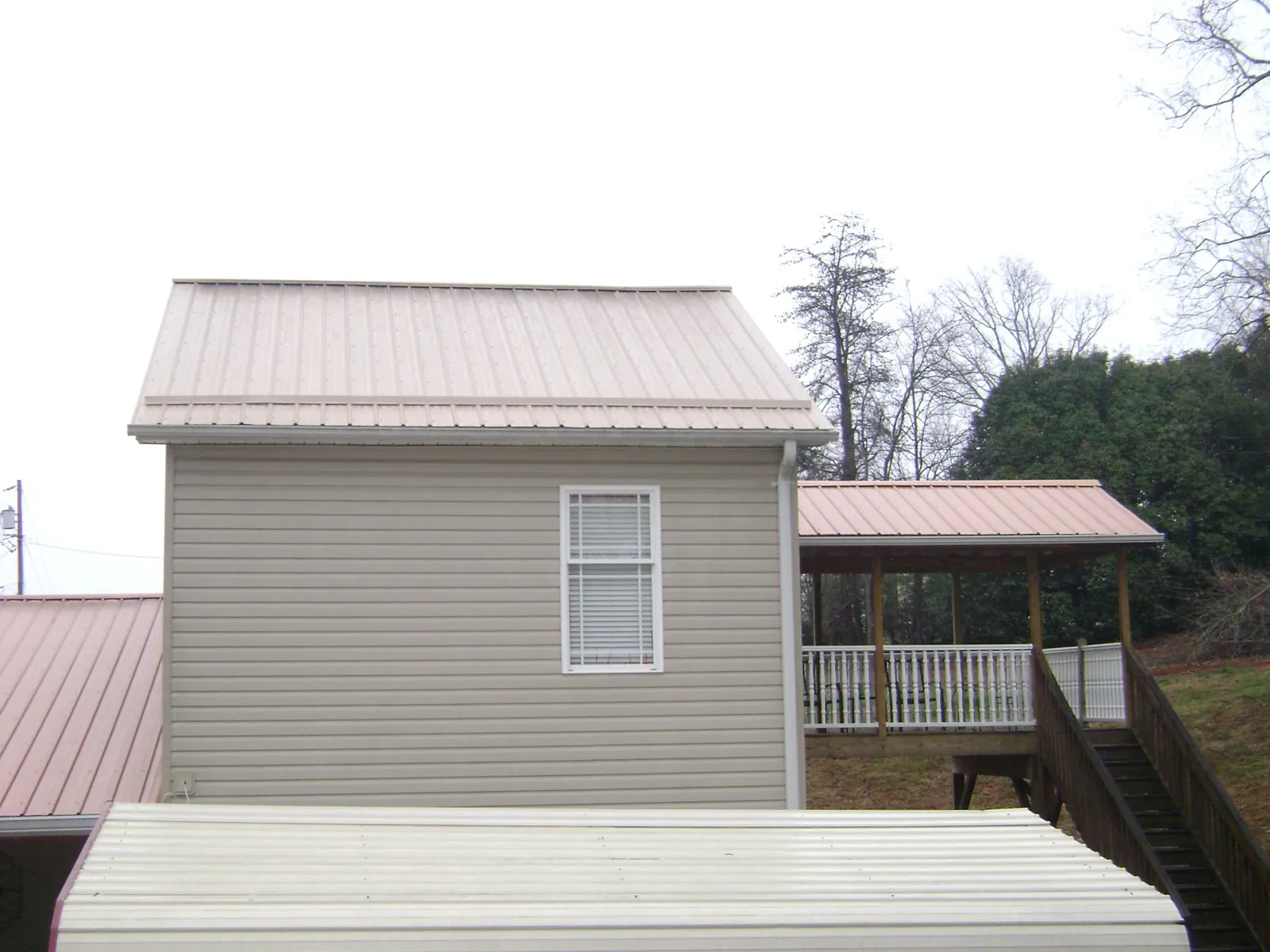 Tan metal roofs on a two story addition and attached porch, from a Roof Replacement job in Ringgold